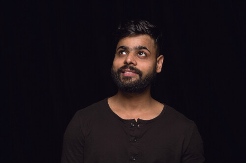 Close up portrait of young man isolated on black studio background. Photoshot of real emotions of male model. Dreaming and smiling, hopeful and happy. Facial expression, human emotions concept.